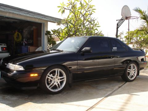 1989 Mazda MX-6 - Black 1989 Mazda MX-6 GT coupe parked in a driveway with a garage in the background.