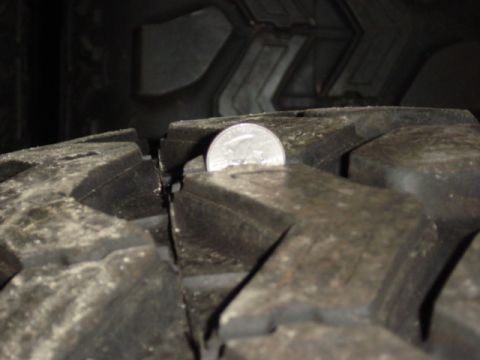 1987 Suzuki Samurai - A quarter is placed in the tread of a tire, likely to show depth or wear.