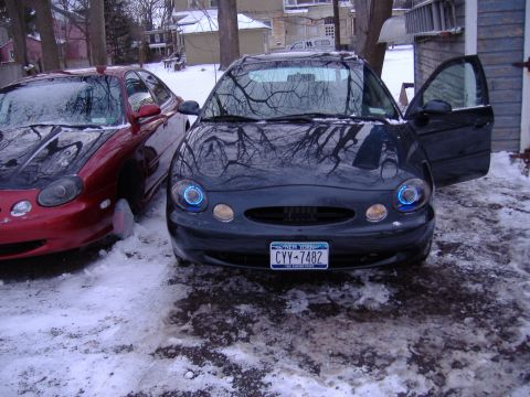 1998 Ford Taurus - Two Ford Taurus sedans are parked outside in the snow, one with its doors open.