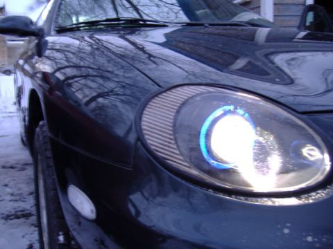 1998 Ford Taurus - Close-up of a dark blue 1998 Ford Taurus, highlighting its distinctive halo headlights and front corner design.
