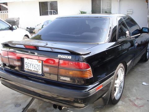 1989 Mazda MX-6 - This black Mazda MX-6 Turbo has a spoiler and a California license plate.
