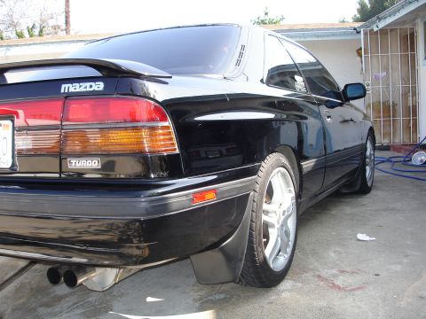 1989 Mazda MX-6 - Rear view of a black 1989 Mazda MX-6, showing its distinctive taillights and dual exhaust pipes.