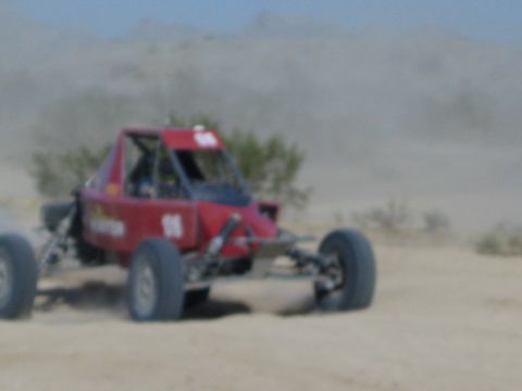 Red off-road race buggy speeding on a hazy dusty desert course