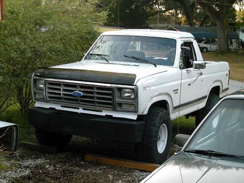 1986 Ford Bronco - This 1980s Ford Bronco is parked outdoors next to another vehicle.