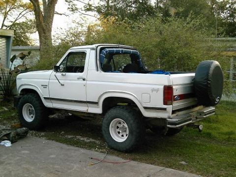 1986 Ford Bronco - This 1986 Ford Bronco is parked on a driveway with trees and bushes in the background.