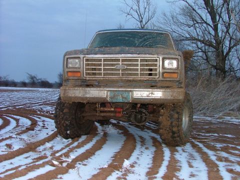 1985 Ford Bronco - This lifted 1980s Ford Bronco is covered in mud and driving through a snowy, plowed field.