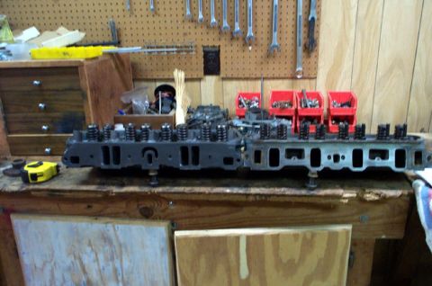 1978 Dodge Power Ram - Engine cylinder heads are displayed on a workbench, with various tools and storage bins visible.
