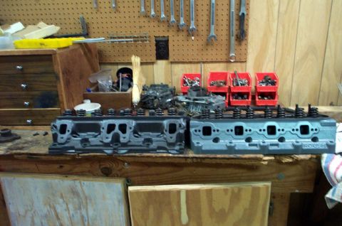 1978 Dodge Power Ram - Engine cylinder heads are displayed on a workbench with tools and parts in the background.