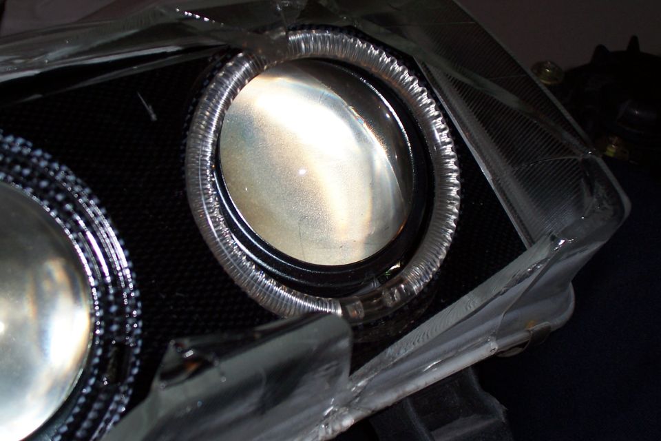 Close-up of a car headlight projector with a halo ring