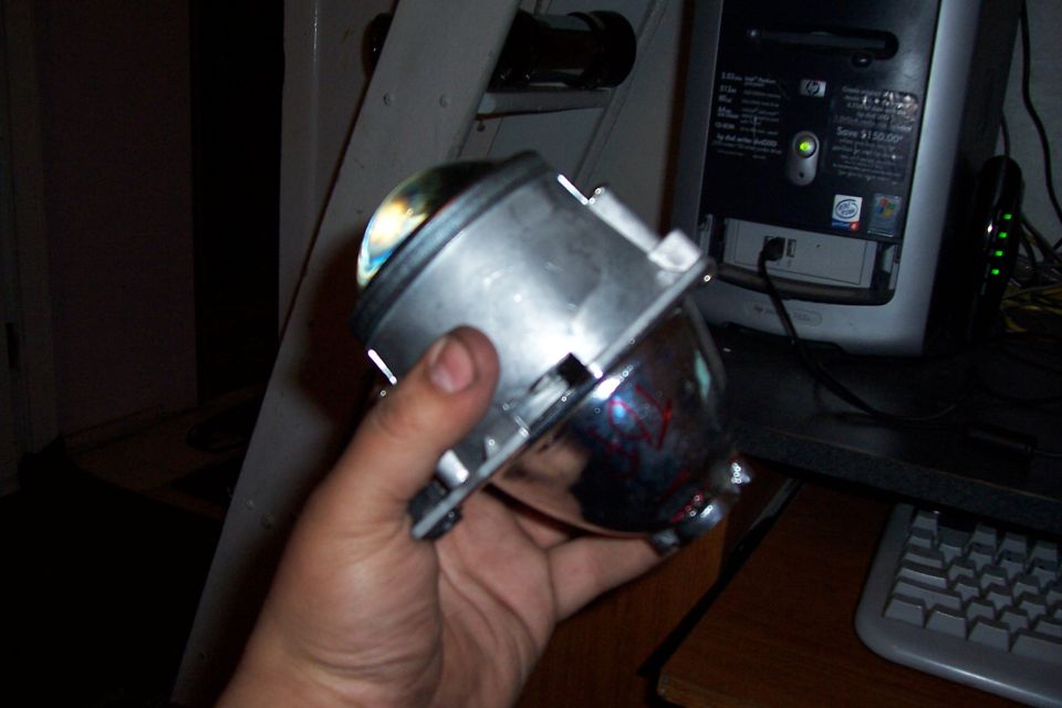 Hand holding a projector headlight assembly with a chrome reflector