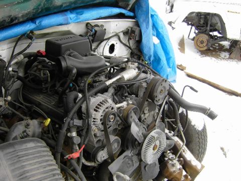 1991 Ford Bronco - Engine bay components are visible, with a blue tarp covering some of the engine. Another vehicle is partially visible in the background.