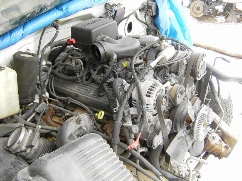 1991 Ford Bronco - Engine assembly with visible hoses, belts, and components. A blue tarp is in the background.