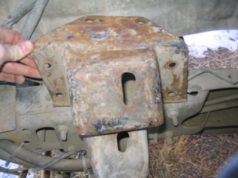 1979 Ford F-150 - Close-up of a heavily rusted metal bracket attached to the underside of a vehicle's frame.