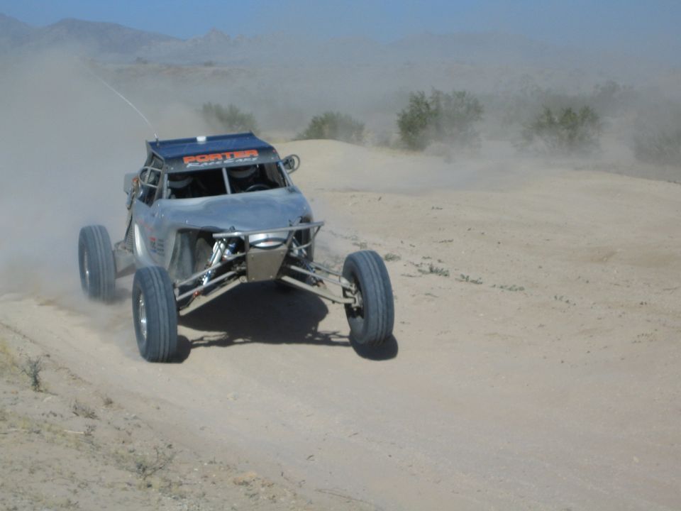 Silver and gray off-road race buggy speeding on a dusty desert track