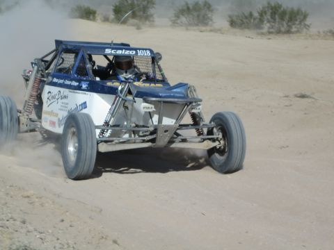 Blue and white off-road race buggy number 1018 cornering in the desert