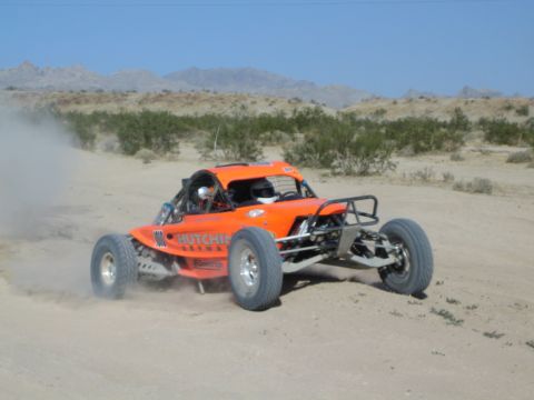 Orange off-road race buggy with Hutchins lettering on a desert course