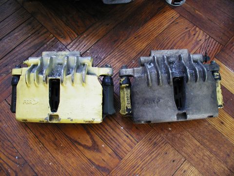 1992 Ford Taurus - Comparison of two brake calipers, one painted yellow and the other showing wear.