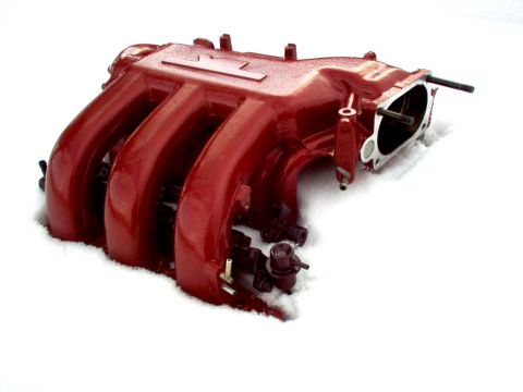 1994 Ford Probe - A red intake manifold sits in the snow, with a visible logo for Supermotors.net.
