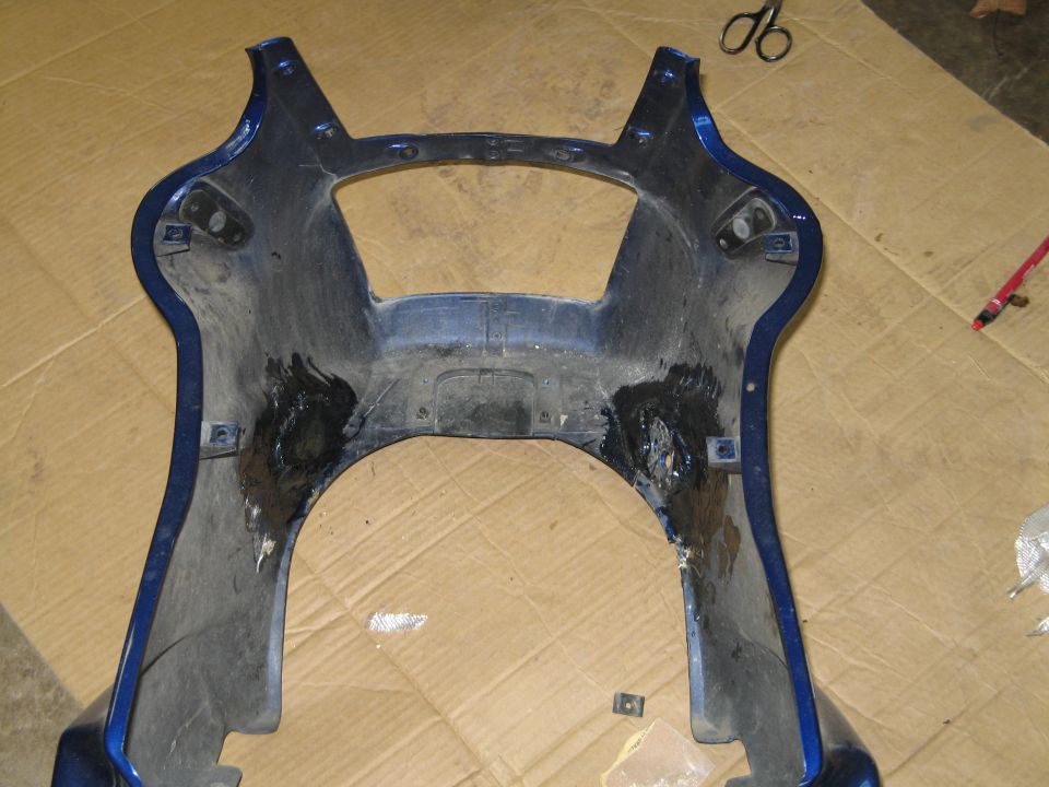 Inner side of a blue motorcycle upper fairing with black resin repairs at the mount points