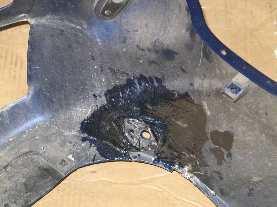 Close-up of a resin and fiberglass repair around a broken mount hole in a blue fairing