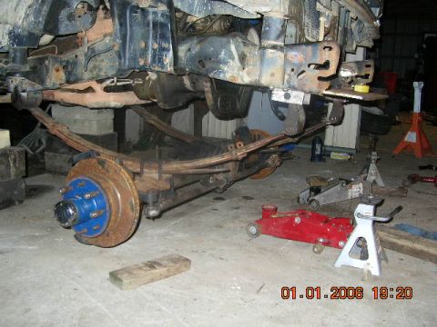 1991 Ford F-150 - Underbody of a vehicle undergoing repair, showing suspension components and tools.