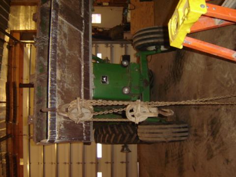 1992 Ford Bronco - A green tractor is partially obscured by chains and pulleys, suggesting it is being worked on or moved.