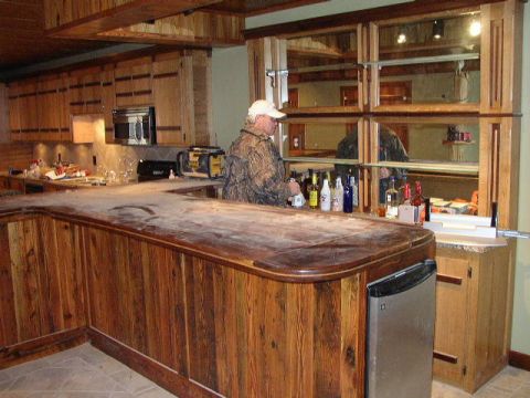 1995 Ford Bronco - A person stands behind a rustic wooden bar in a room with wood-paneled cabinets and mirrored shelving.