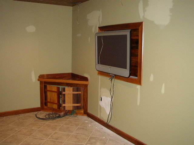 Interior scene with mounted television and wooden corner cabinet