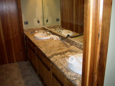 1995 Ford Bronco - Bathroom vanity area with granite countertop, double sinks, and wooden paneling.