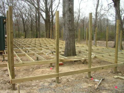 1995 Ford Bronco - Construction of a wooden deck is underway, with framing visible around a mature tree in a forest setting.