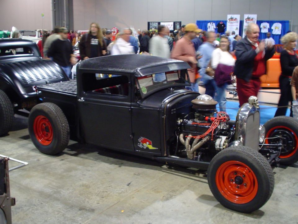 Black hot rod pickup truck with exposed engine and red wheels