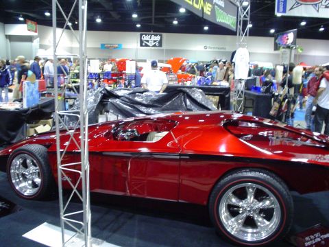1984 Ford Bronco - A heavily modified red car with custom wheels is displayed indoors, not a 1984 Ford Bronco.