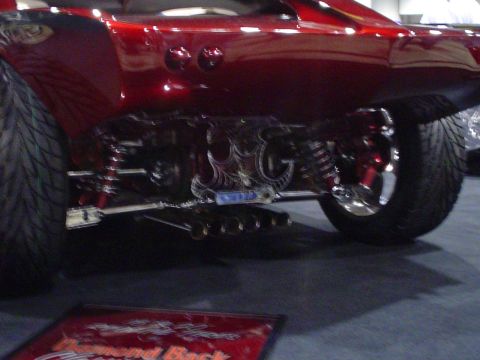 1984 Ford Bronco - Detail of a custom rear suspension and exhaust system on a vehicle, likely at a car show.