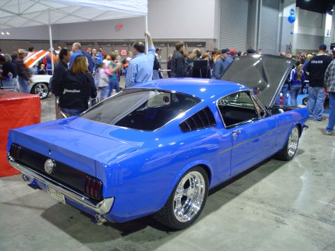 1984 Ford Bronco - A bright blue 1965 Ford Mustang coupe is displayed indoors with its hood open, its engine bay.