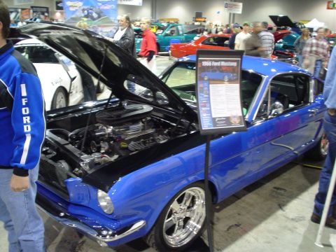 1984 Ford Bronco - A blue 1966 Ford Mustang is displayed with its hood open, revealing the engine, at a car show.