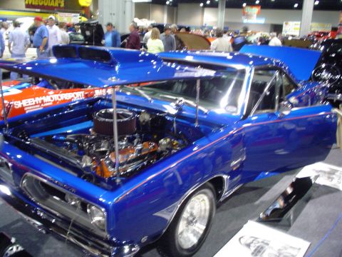 1984 Ford Bronco - A bright blue muscle car is displayed with its hood and door open, revealing the engine bay.