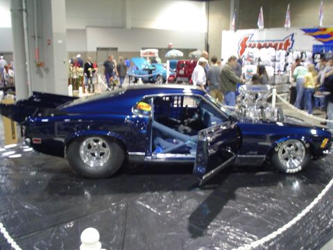 1984 Ford Bronco - A modified blue drag car with a large engine and racing interior is on display at an indoor event.