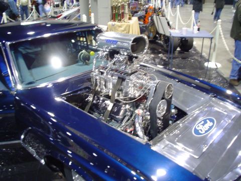 1984 Ford Bronco - A custom blue car with a prominent exposed engine and a Ford logo on the engine cover is displayed indoors.