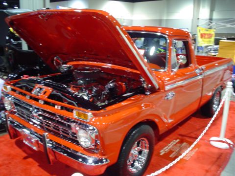 1984 Ford Bronco - This orange 1965 Ford F-100 pickup truck is displayed with its hood open.