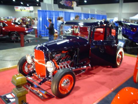 1984 Ford Bronco - A custom hot rod with exposed engine and bright red interior is displayed on a red carpet.