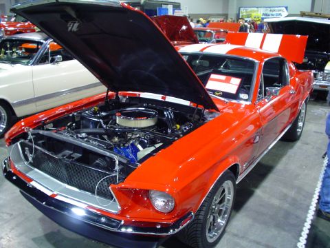 1984 Ford Bronco - This orange 1967 Ford Mustang fastback is displayed with its hood open, revealing the engine and prominent racing stripes.