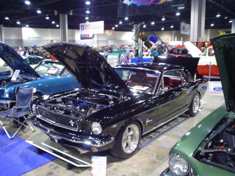 1984 Ford Bronco - A black 1965 Ford Mustang coupe is displayed with its hood open, revealing the engine bay.