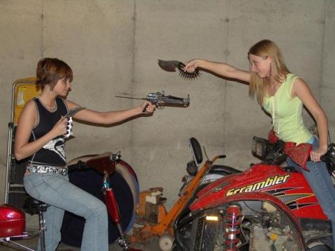 1998 Jeep TJ - Two women pose with prop weapons on ATVs in a garage setting.