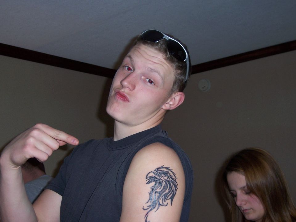 Man with eagle tattoo pointing, sunglasses on head
