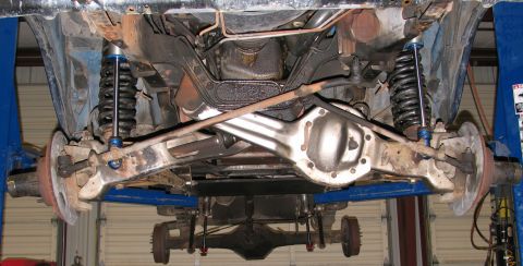 1984 Ford Bronco - The underside of a vehicle is visible, with suspension components and a rear axle assembly.