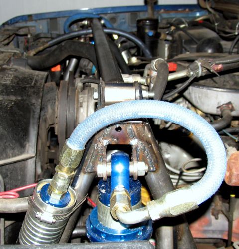 1984 Ford Bronco - Close-up view of an engine bay, a blue shock absorber and braided hoses.