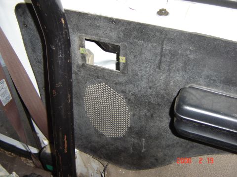 1993 Ford Bronco - Close-up of a vehicle's interior door panel, showing a speaker grille and an empty mounting bracket.