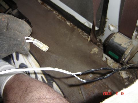1993 Ford Bronco - Close-up of wiring work inside a vehicle, showing a gloved hand connecting wires near the seatbelt mechanism.