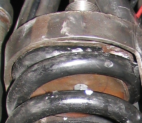 1984 Ford Bronco - Detail of a vehicle's suspension system, focusing on the coil spring and mounting hardware.