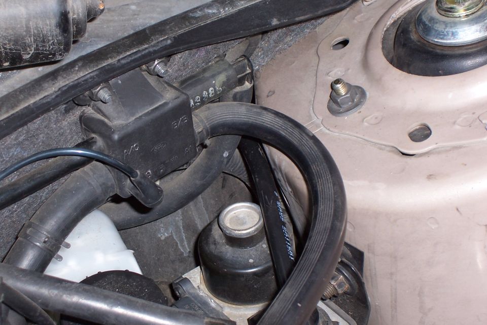 close-up of engine bay showing vacuum lines, a black box with 'A/C' and 'EVAP' labels, and a small black canister